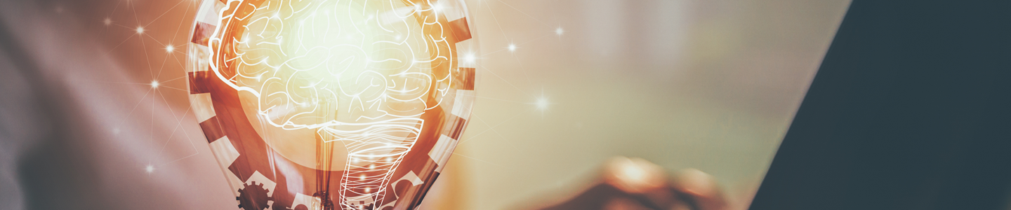 A person sitting in the background with one hand on a computer keyboard and the other hand holding an illustration of a light bulb, with gears, filament and white outline of a human brain with sparks of light connected by lines around it.