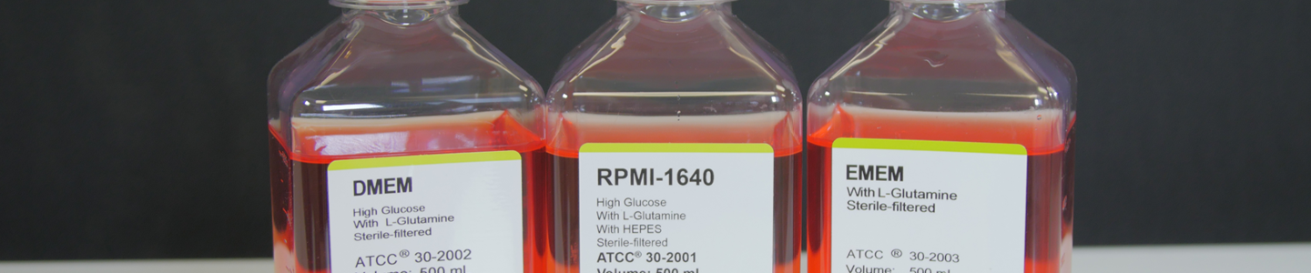 Capped clear bottles containing orange media, labeled: DMEM; RPMI-1640 high glucose with L-glutamine with HEPES; and EMEM.