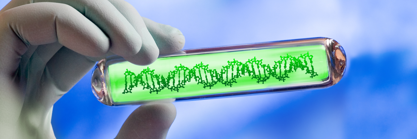 Hand holding clear tube that contains DNA strand in neon green substance.