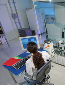 Overhead back view of ATCC scientist sitting at computer station near machinery in lab.
