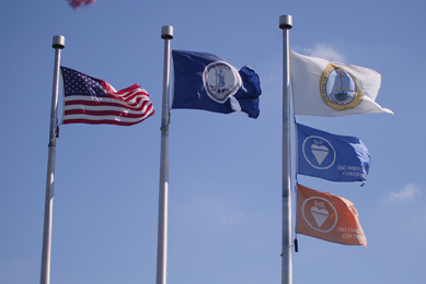 Three flag poles with American flag, Commonwealth of Virginia, Prince William County, and two BSI ISO certified flags.