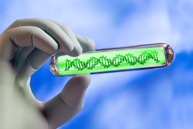 Hand holding clear tube that contains DNA strand in neon green substance.