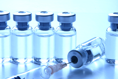 Clear vials sealed with silver caps, one vial lying on its side being punctured by syringe.