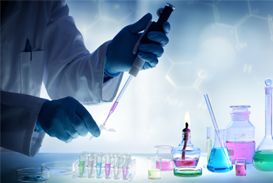 Scientist using pipette to put pink liquid into small tube, bottles full of various colored liquids on table nearby.