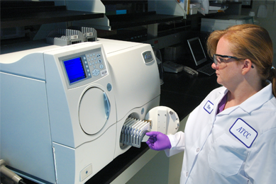Female ATCC scientist opening door of Vitek2 microbial identification and antibiotic susceptibility testing equipment.