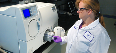 Female ATCC scientist opening door of Vitek2 microbial identification and antibiotic susceptibility testing equipment.