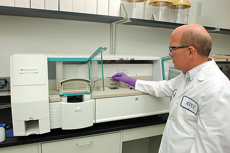ATCC scientist in lab coat, wearing gloves at ribo printer.